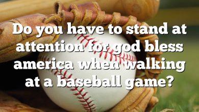 Do you have to stand at attention for god bless america when walking at a baseball game?